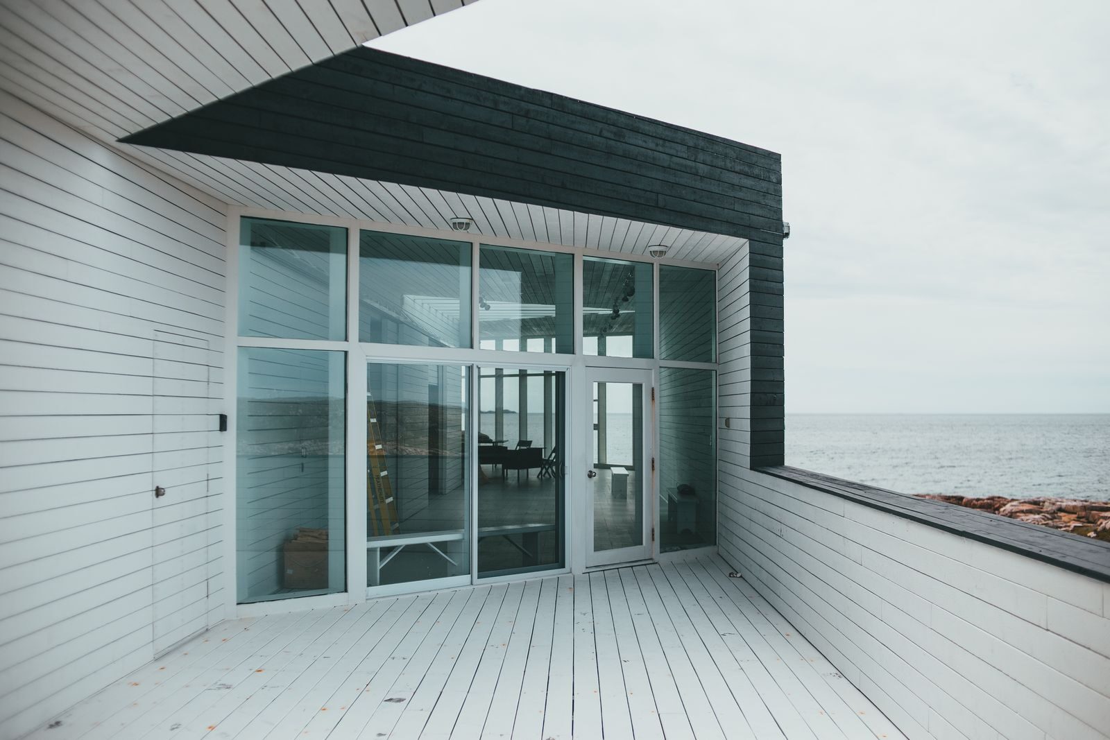 Contemporary seaside house featuring glass doors and ocean view.